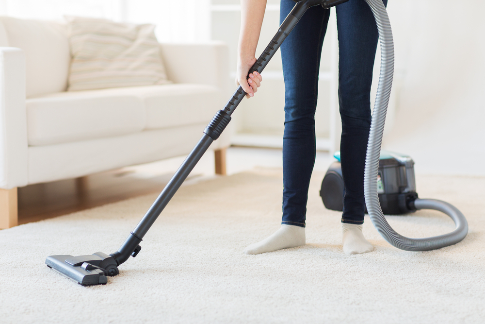 A woman vacuuming a carpet in her home