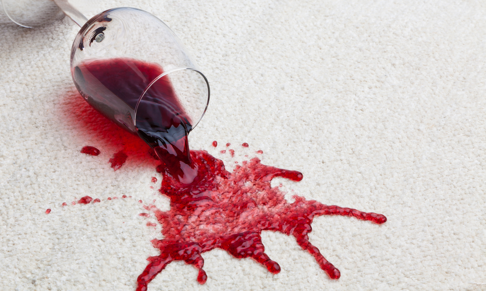 a glass of red wine spilled on a white carpet