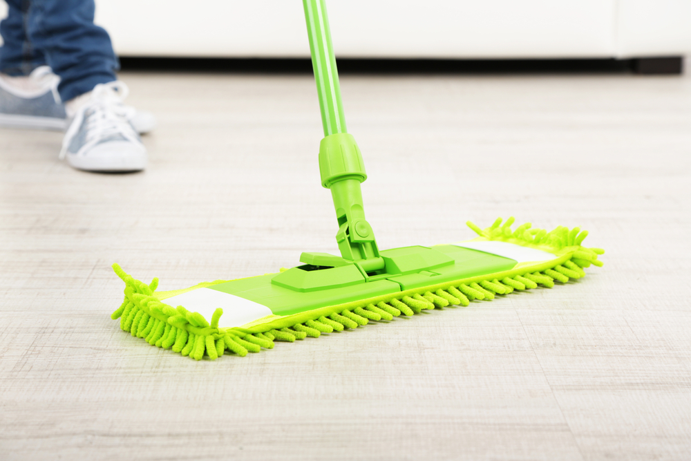 a person using a dust mop to clean hardwood floors