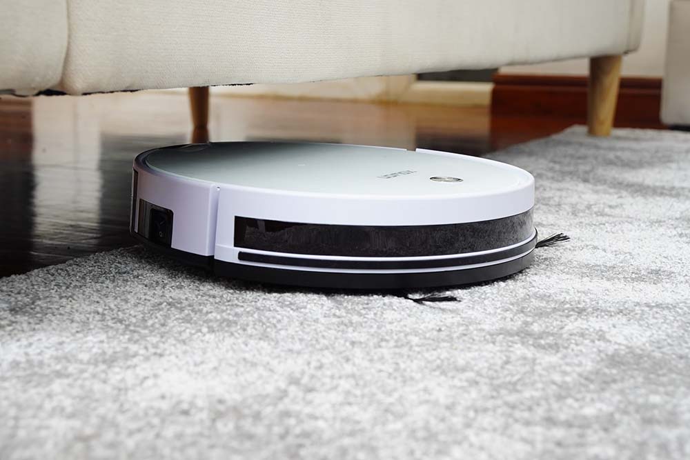  A white robot vacuum cleaner cleaning a gray carpet