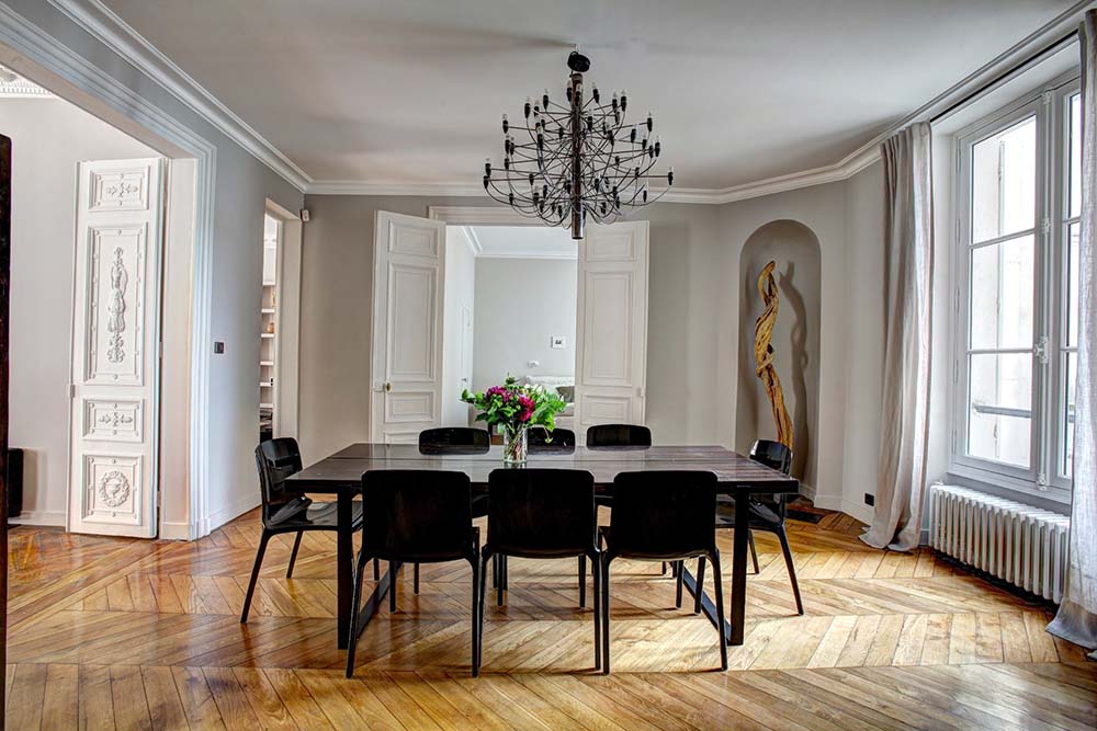 A dining room with light wooden floors and dark wood dining room furniture.