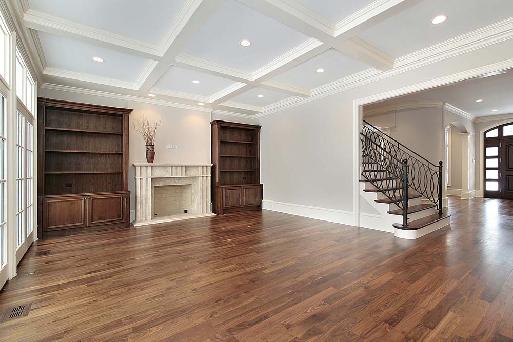 A family room without furniture with neutral, mid-tone brown hardwood floors.