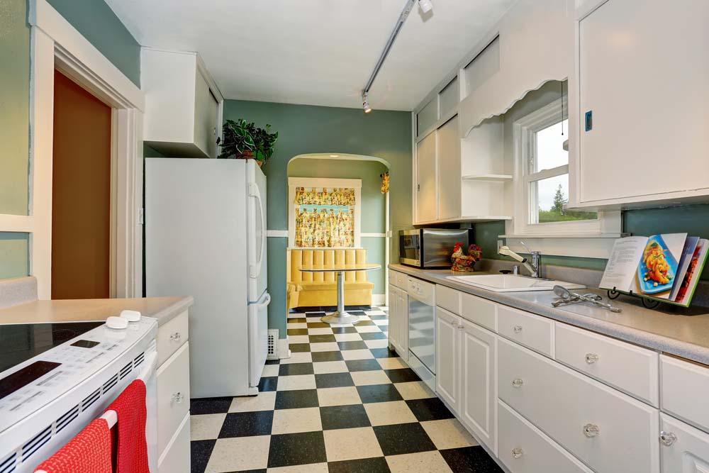 A kitchen with blue walls, white cabinetry, and black and white checkerboard floors.