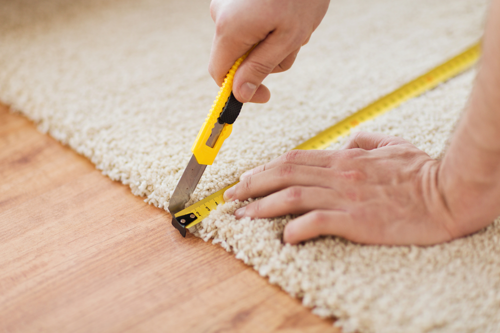 Hands of a man measuring carpet flooring