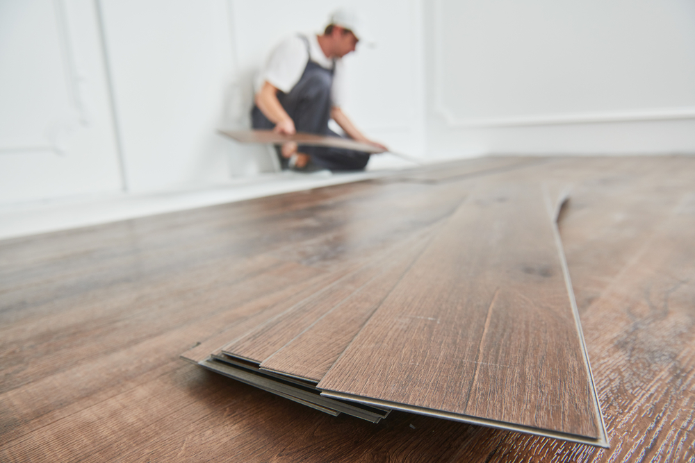 worker laying vinyl flooring