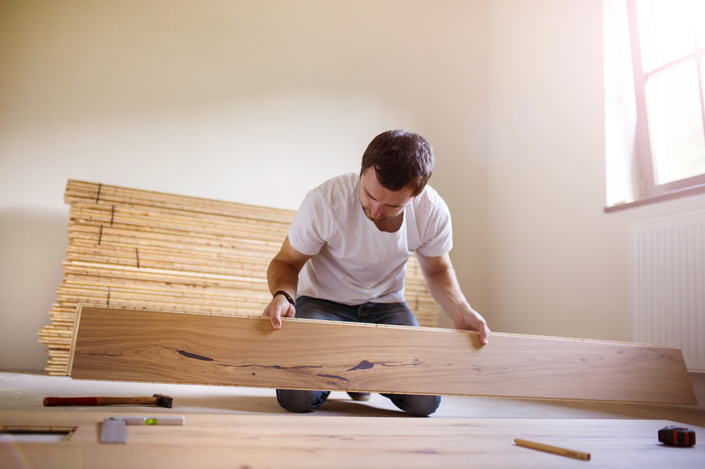 A man installs planks on a hardwood floor